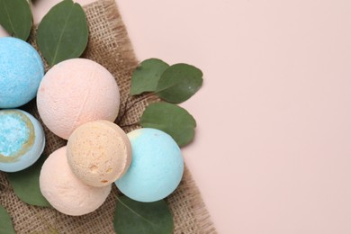 Bath bombs, eucalyptus leaves and burlap fabric on beige background, flat lay. Space for text