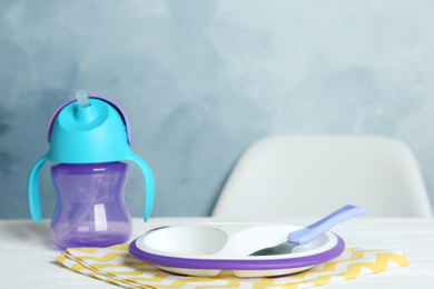 Photo of Set of plastic dishware on white table. Serving baby food