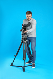 Operator with professional video camera on blue background