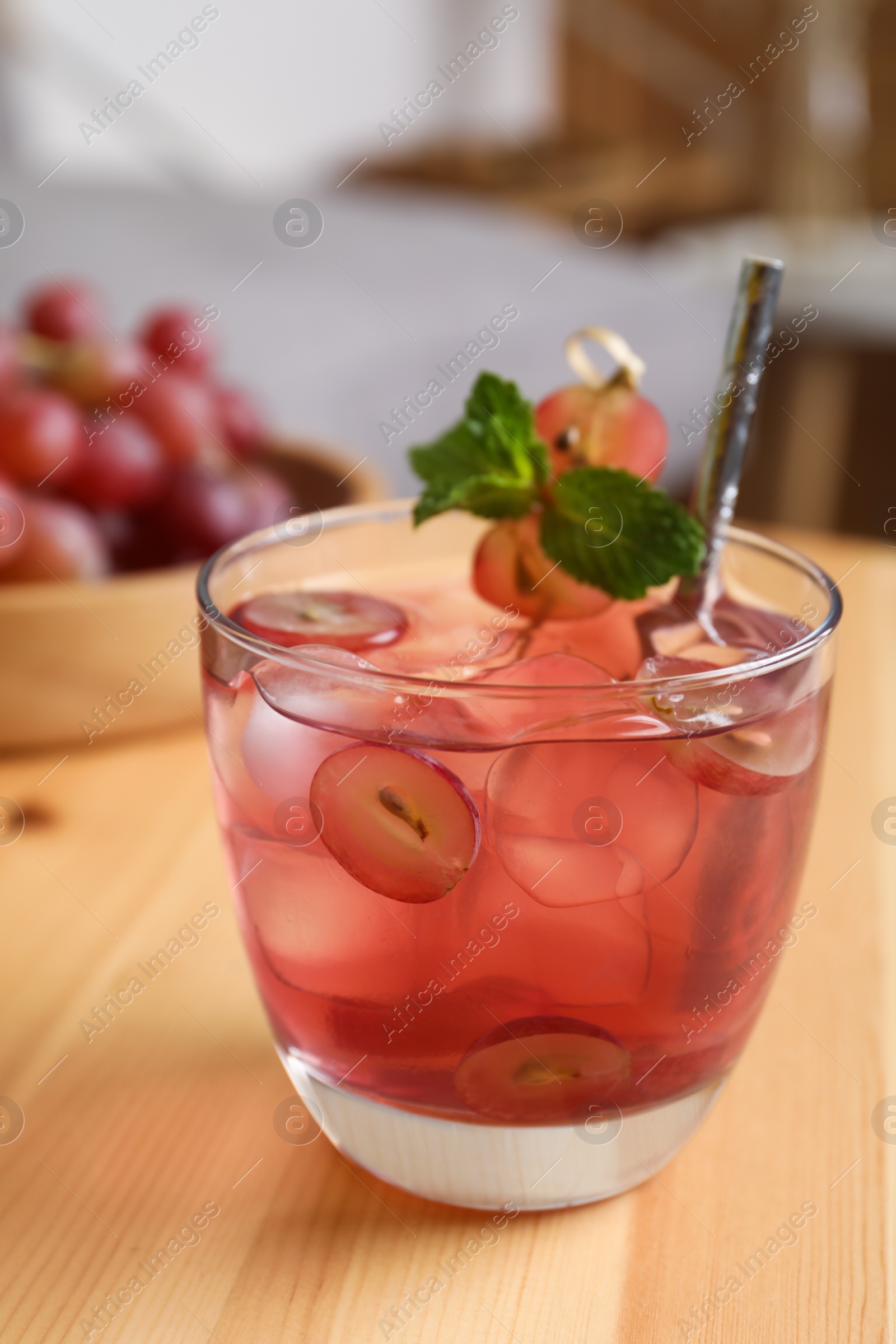 Photo of Refreshing drink with soda water, grapes, ice and mint on wooden table indoors