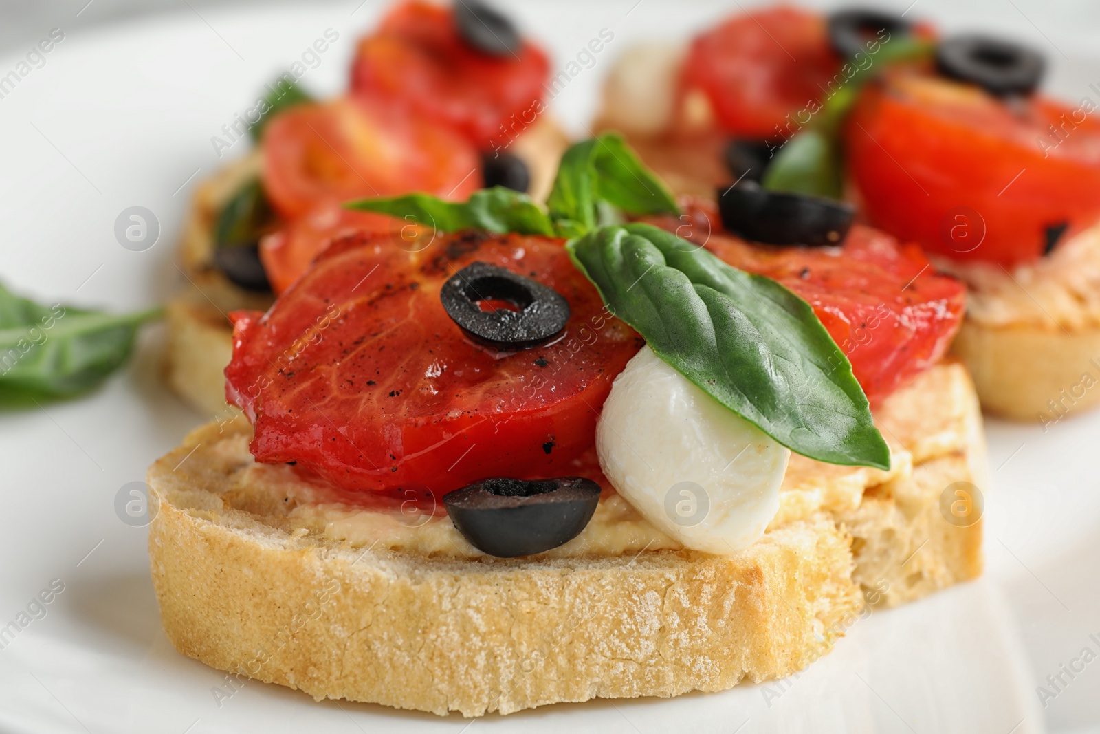 Photo of Delicious tomato bruschettas on white plate, closeup