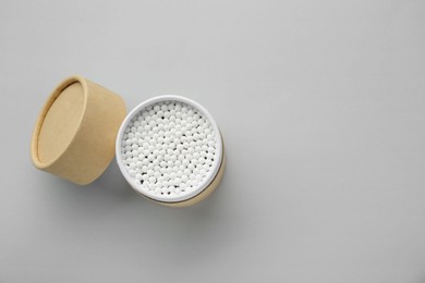 Container with new cotton buds on light grey background, top view. Space for text