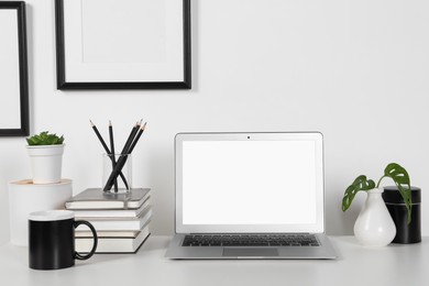 Home workplace. Laptop, stationery and houseplants on white wooden desk