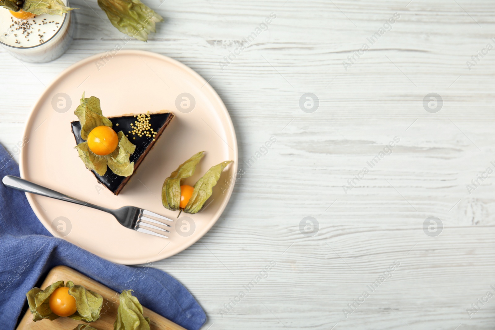 Photo of Delicious dessert decorated with physalis fruit on white wooden table, flat lay. Space for text