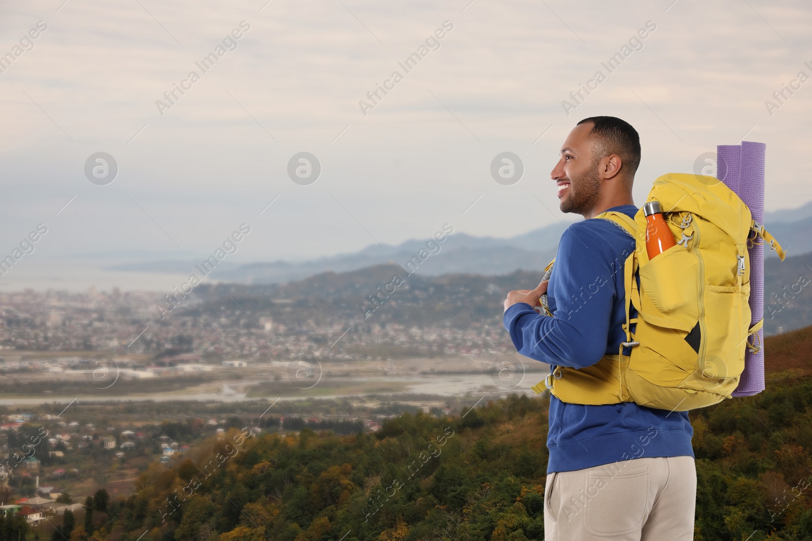 Image of Happy tourist with yellow backpack in mountains