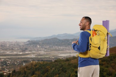 Happy tourist with yellow backpack in mountains