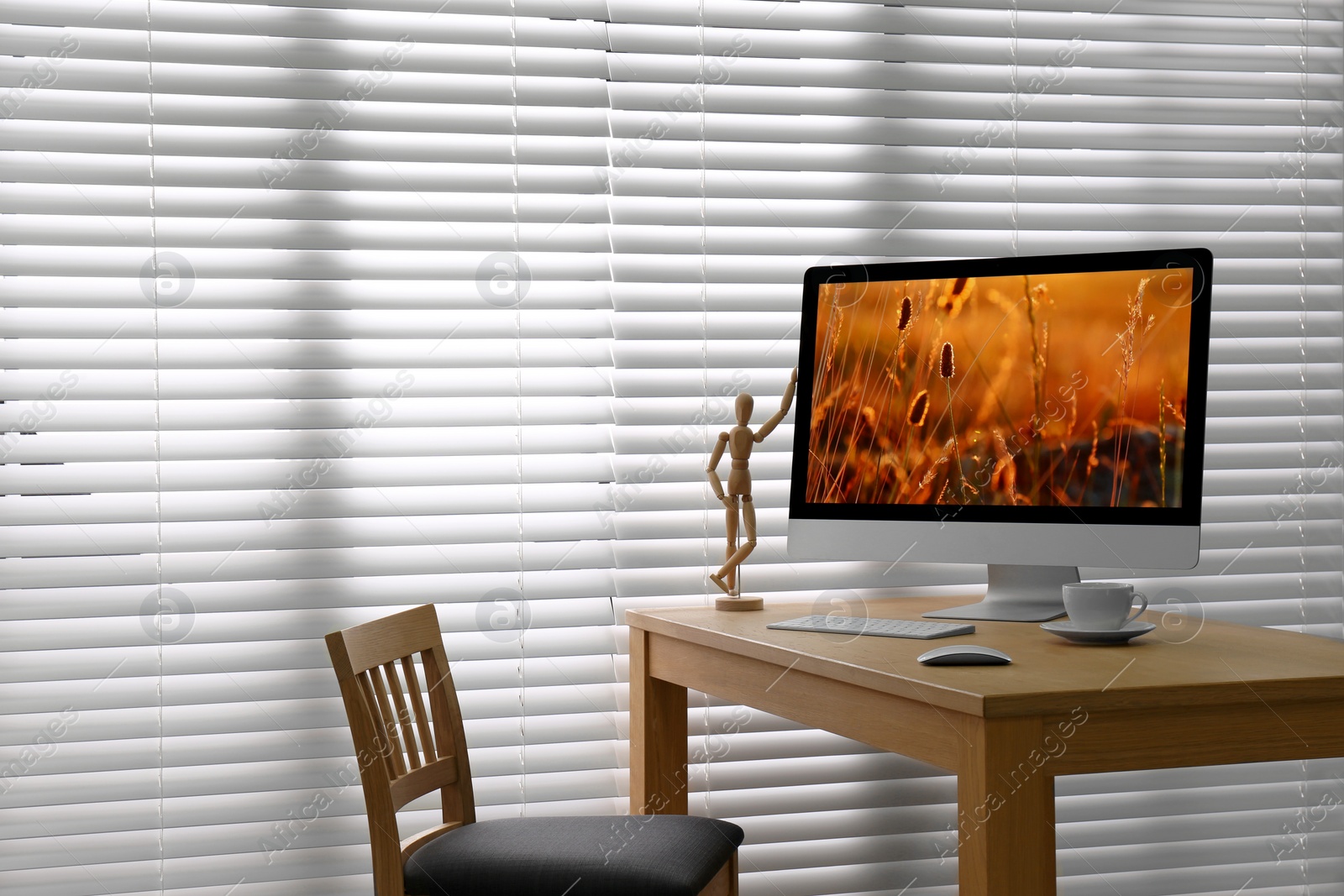 Photo of Modern PC on table near window with blinds in room