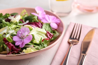 Fresh spring salad with flowers on grey table, closeup