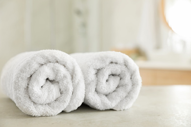 Photo of Clean rolled towels on table in bathroom