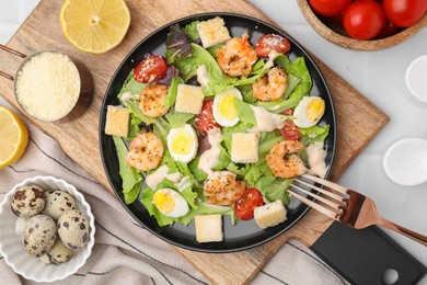 Delicious Caesar salad with shrimps and fork served on white table, flat lay