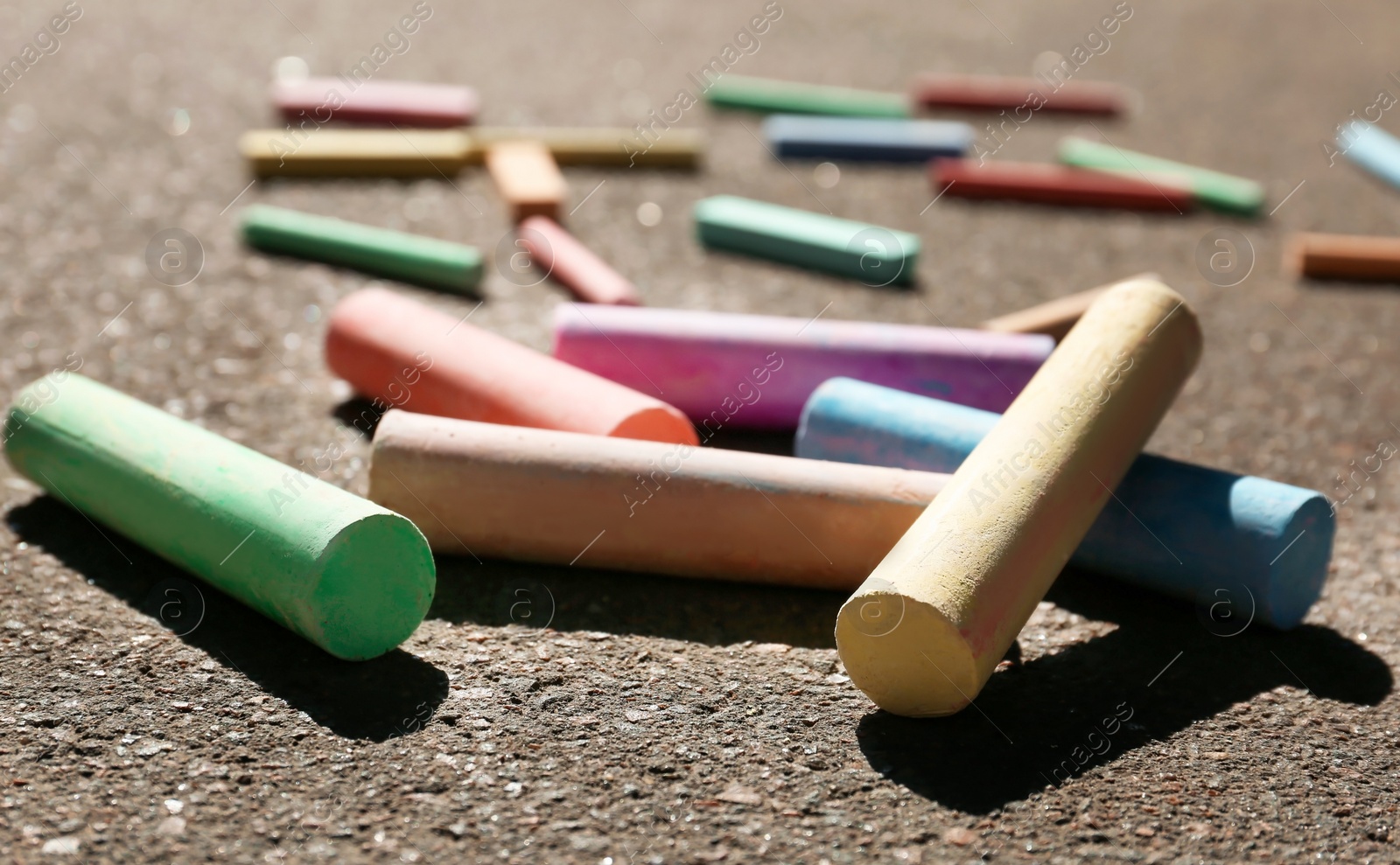 Photo of Many colorful chalk sticks on asphalt, closeup