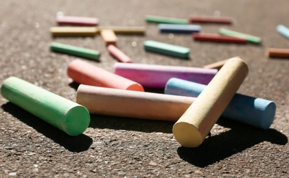 Many colorful chalk sticks on asphalt, closeup