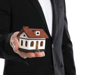 Photo of Real estate agent holding house model on white background, closeup