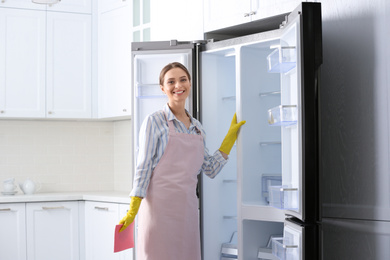 Photo of Woman with rag near clean refrigerator at home