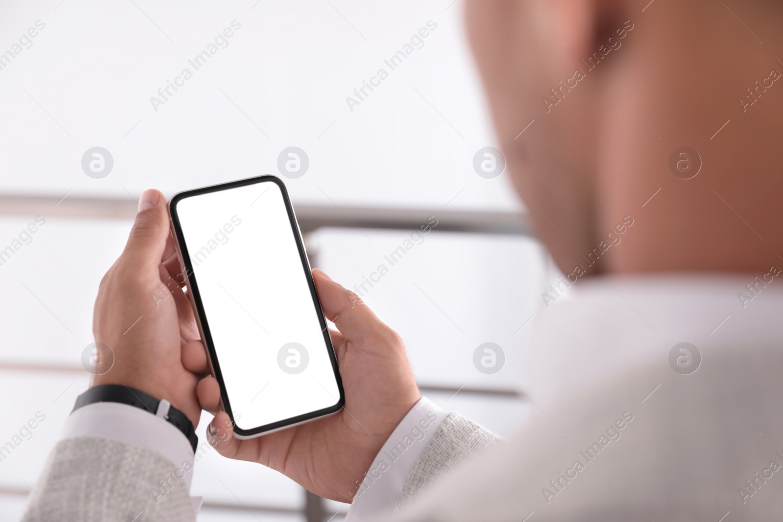 Photo of Man holding mobile phone with empty screen indoors, closeup