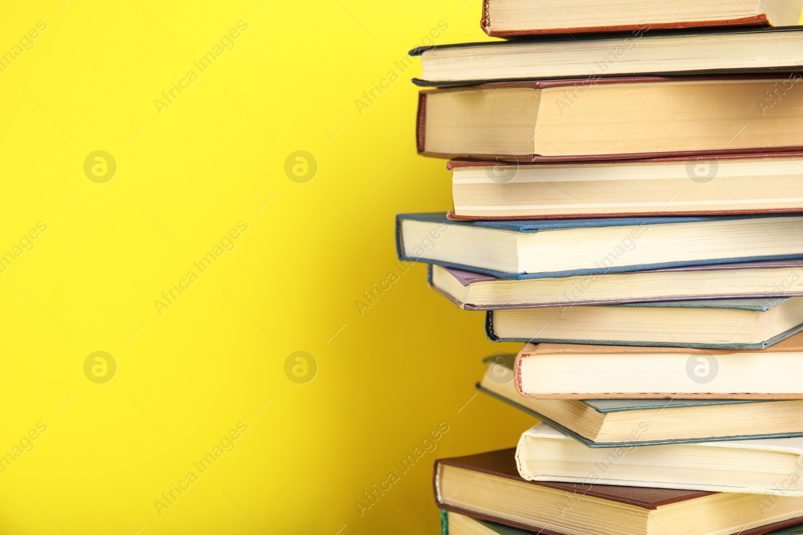 Photo of Stack of hardcover books on yellow background. Space for text