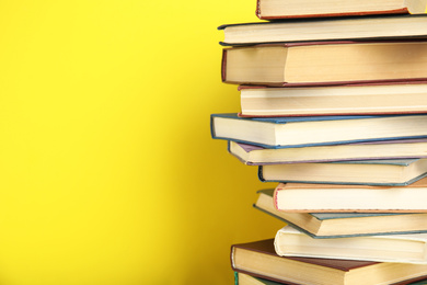 Photo of Stack of hardcover books on yellow background. Space for text