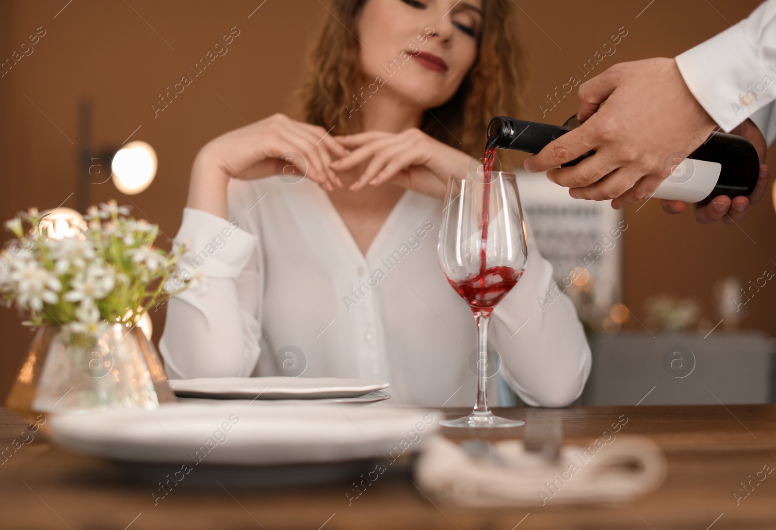 Photo of Waiter pouring wine into glass for client at restaurant