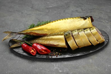 Photo of Delicious smoked mackerels with pepper, dill and spices on dark grey table