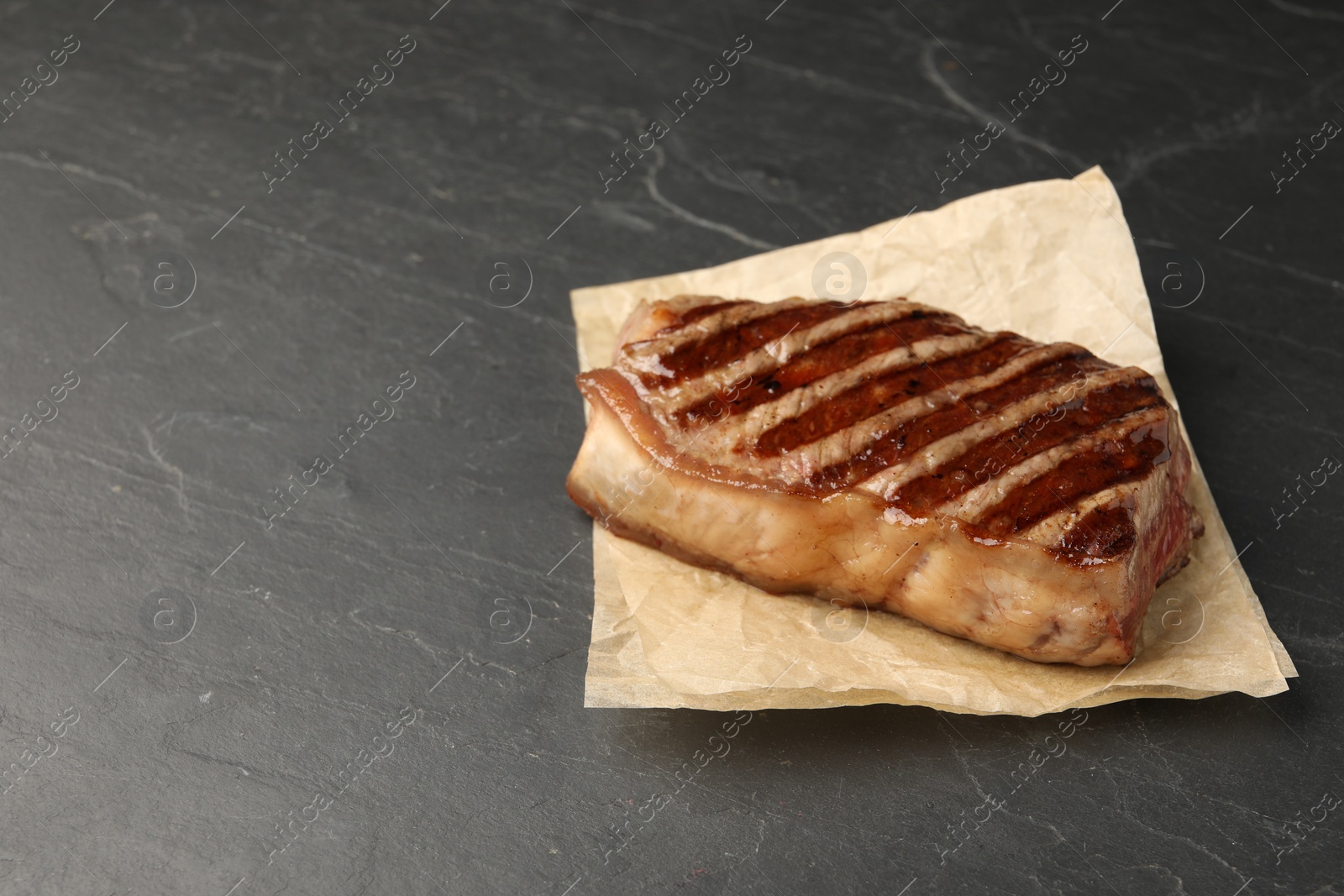 Photo of Delicious grilled beef steak on dark gray table, space for text