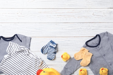 Photo of Flat lay composition with stylish baby clothes and toys on wooden background. Space for text