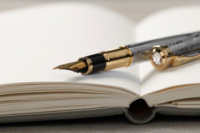 Fountain pen and notebook on wooden table, closeup