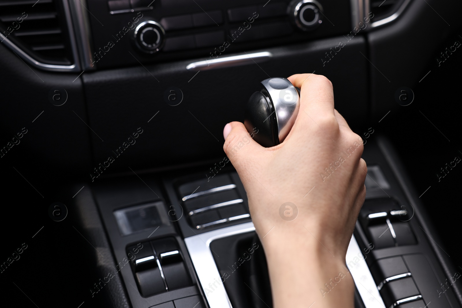 Photo of Woman using gear stick while driving her car, closeup