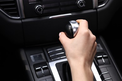 Photo of Woman using gear stick while driving her car, closeup