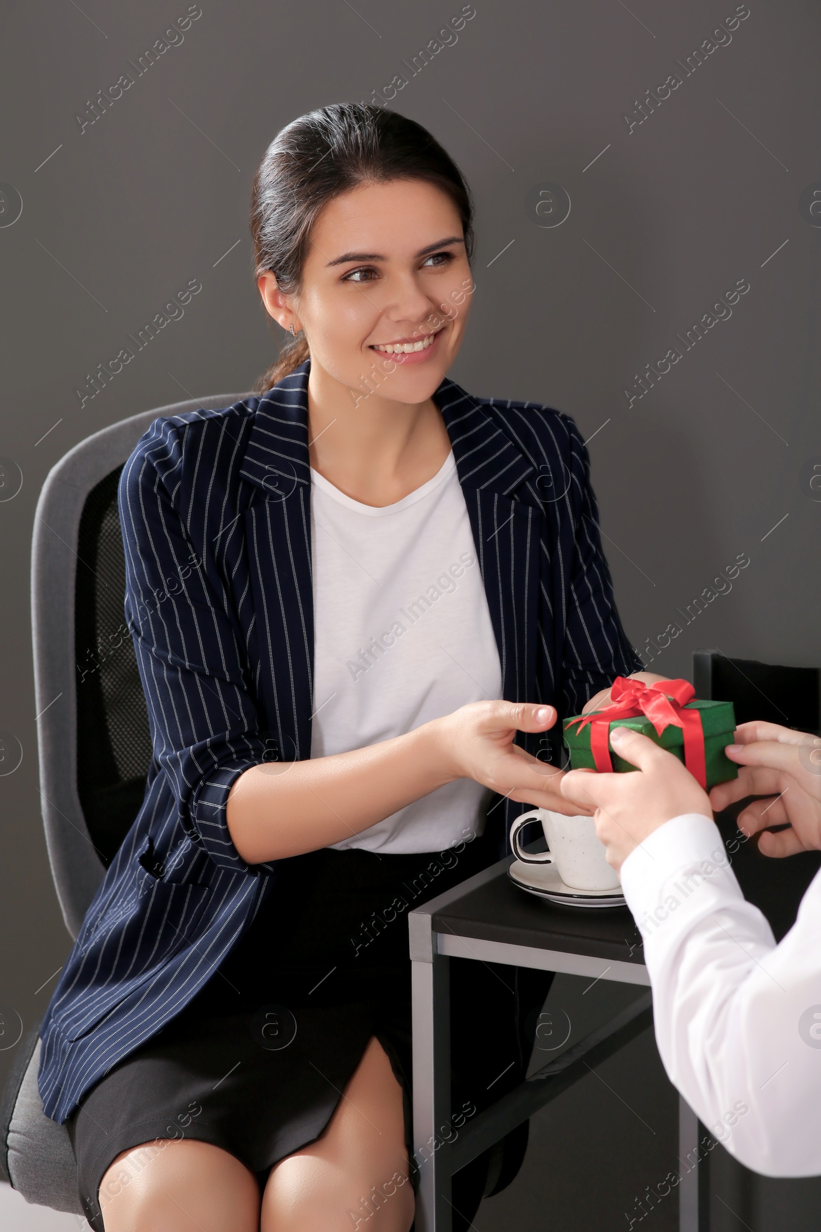 Photo of Woman presenting gift to her colleague in office