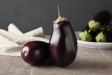 Photo of Ripe purple eggplants on brown marble table, closeup