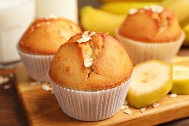 Tasty muffins served with banana on wooden table, closeup