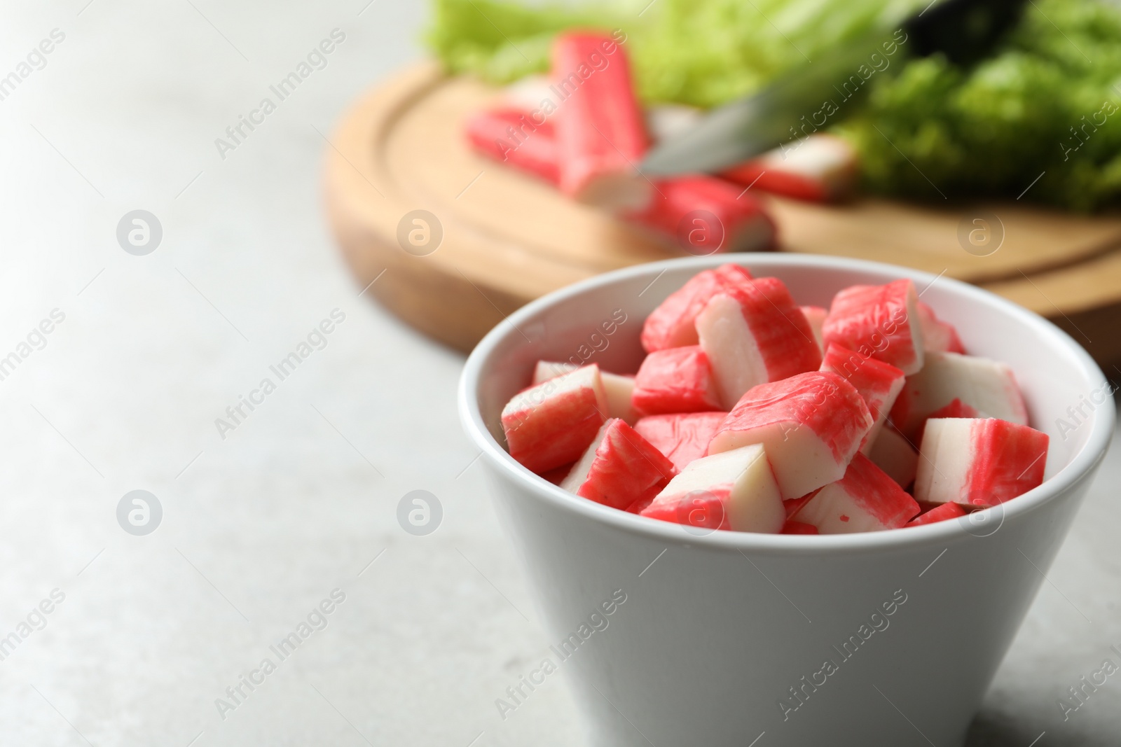 Photo of Cut crab sticks in bowl on light table, closeup. Space for text