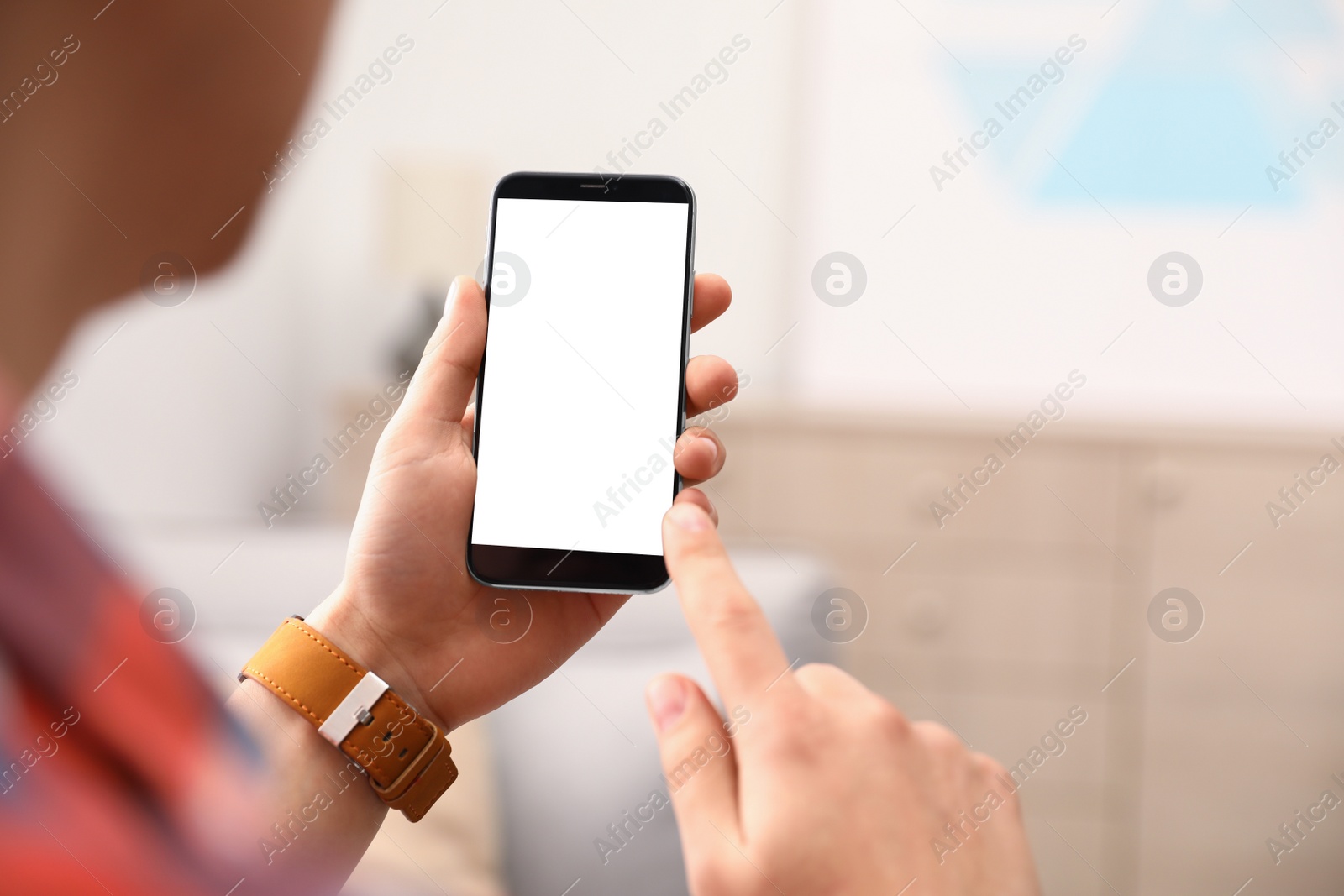 Photo of Man holding smartphone with blank screen indoors, closeup of hands. Space for text