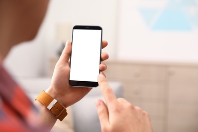 Photo of Man holding smartphone with blank screen indoors, closeup of hands. Space for text