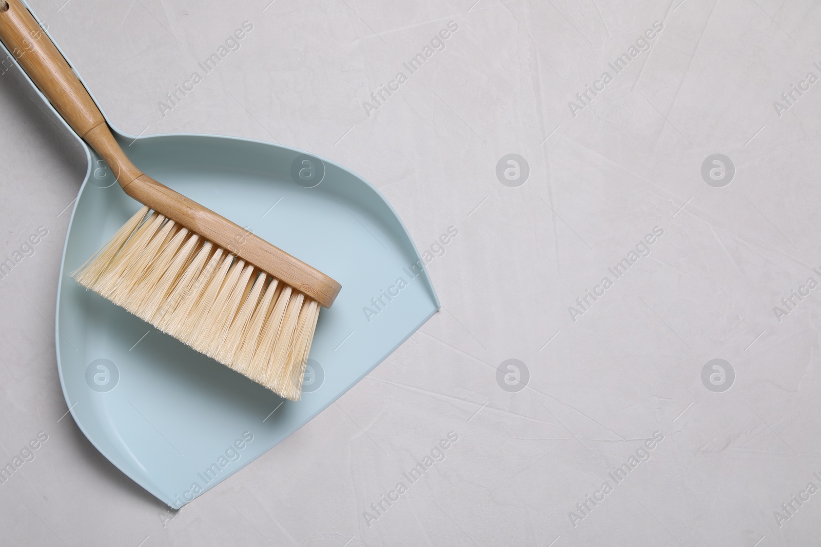 Photo of Cleaning brush and scoop on light grey background, top view. Space for text