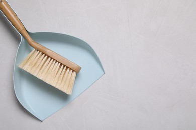 Photo of Cleaning brush and scoop on light grey background, top view. Space for text