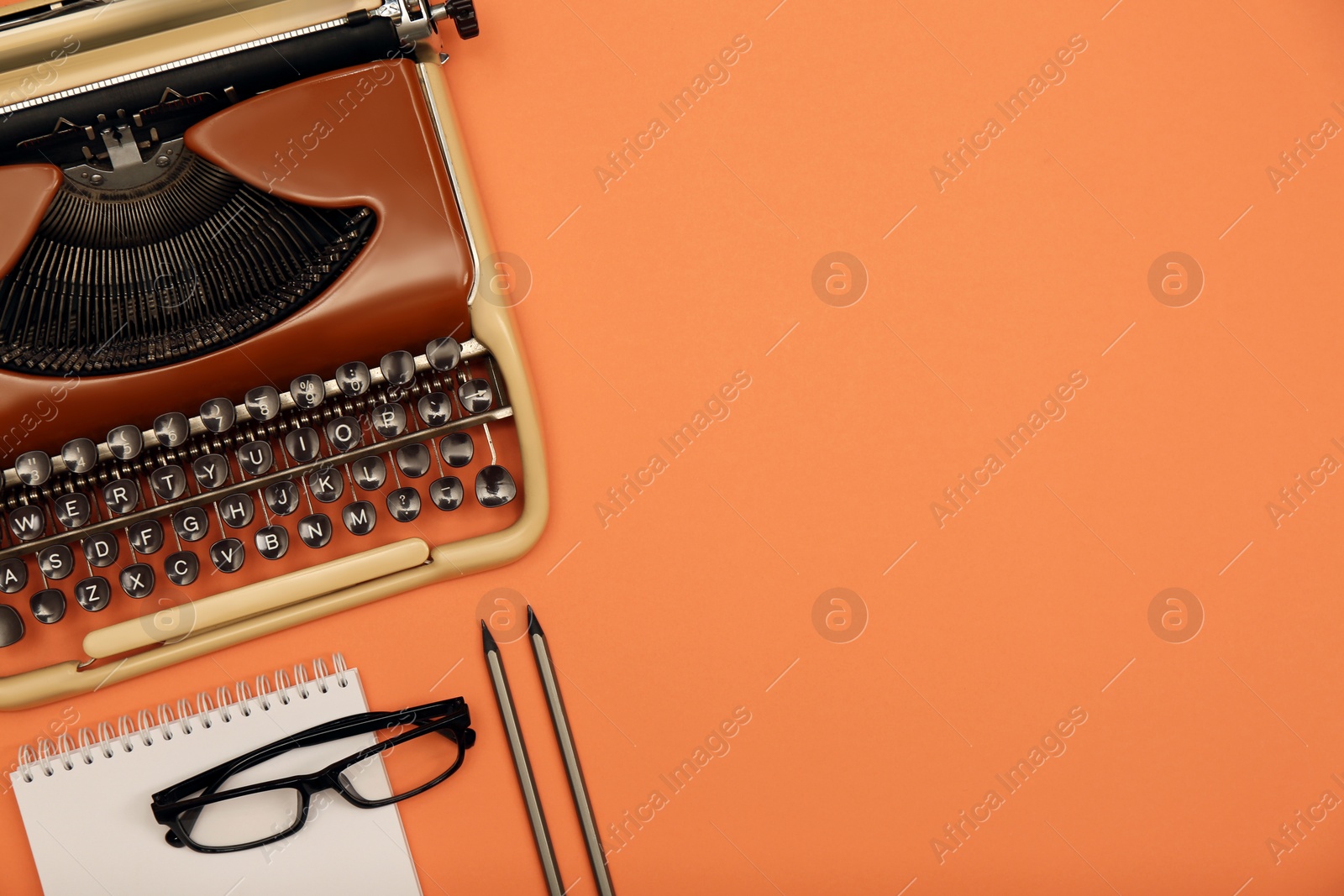 Photo of Vintage typewriter, glasses and stationery on coral background, flat lay. Space for text