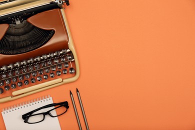 Vintage typewriter, glasses and stationery on coral background, flat lay. Space for text