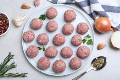 Many fresh raw meatballs on white table, flat lay