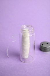 Biodegradable dental floss in glass jar on violet background