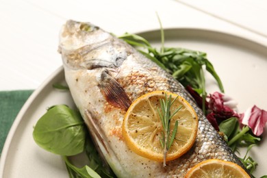 Photo of Baked fish with spinach and lemon on white wooden table, closeup