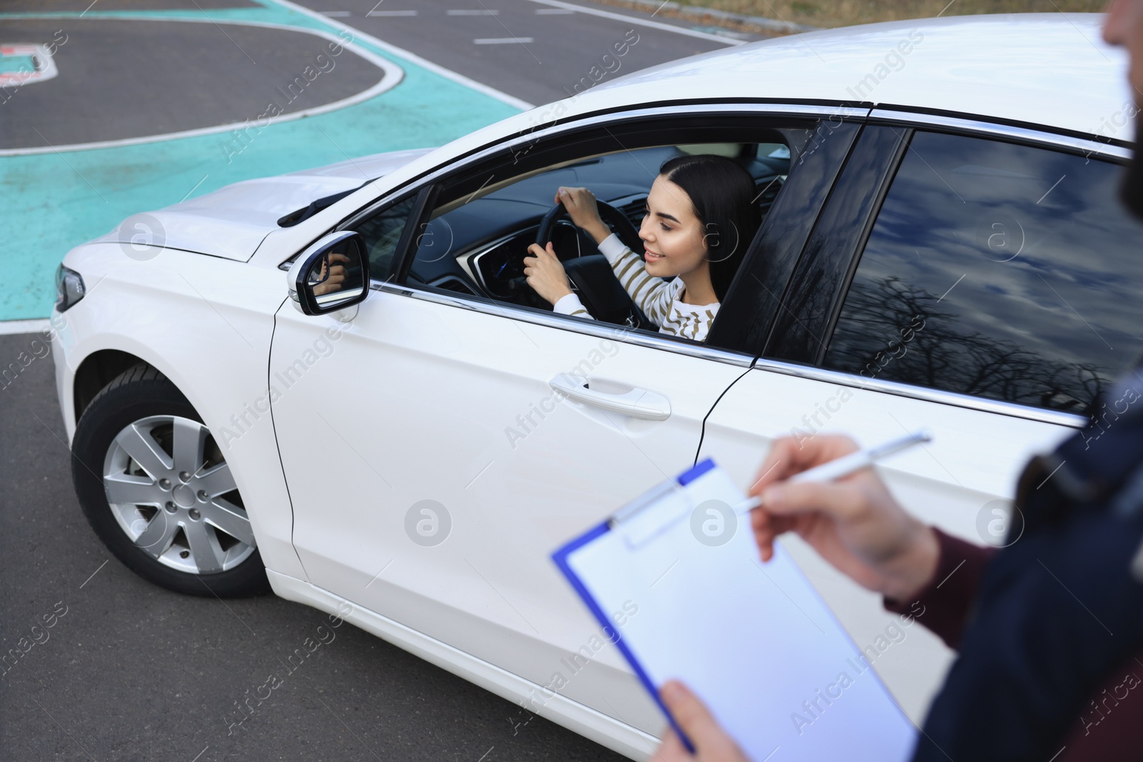 Photo of Instructor near car with his student during exam at driving school test track