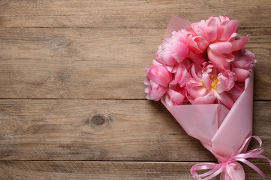 Photo of Beautiful bouquet of pink peonies on wooden table, top view. Space for text