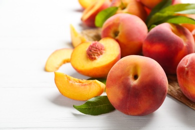 Photo of Fresh sweet peaches on white wooden table, closeup