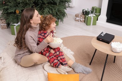 Mother and son with popcorn watching movie via video projector at home