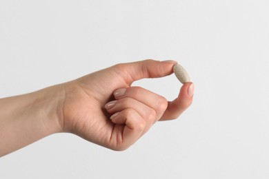 Woman holding vitamin pill on white background, closeup. Health supplement