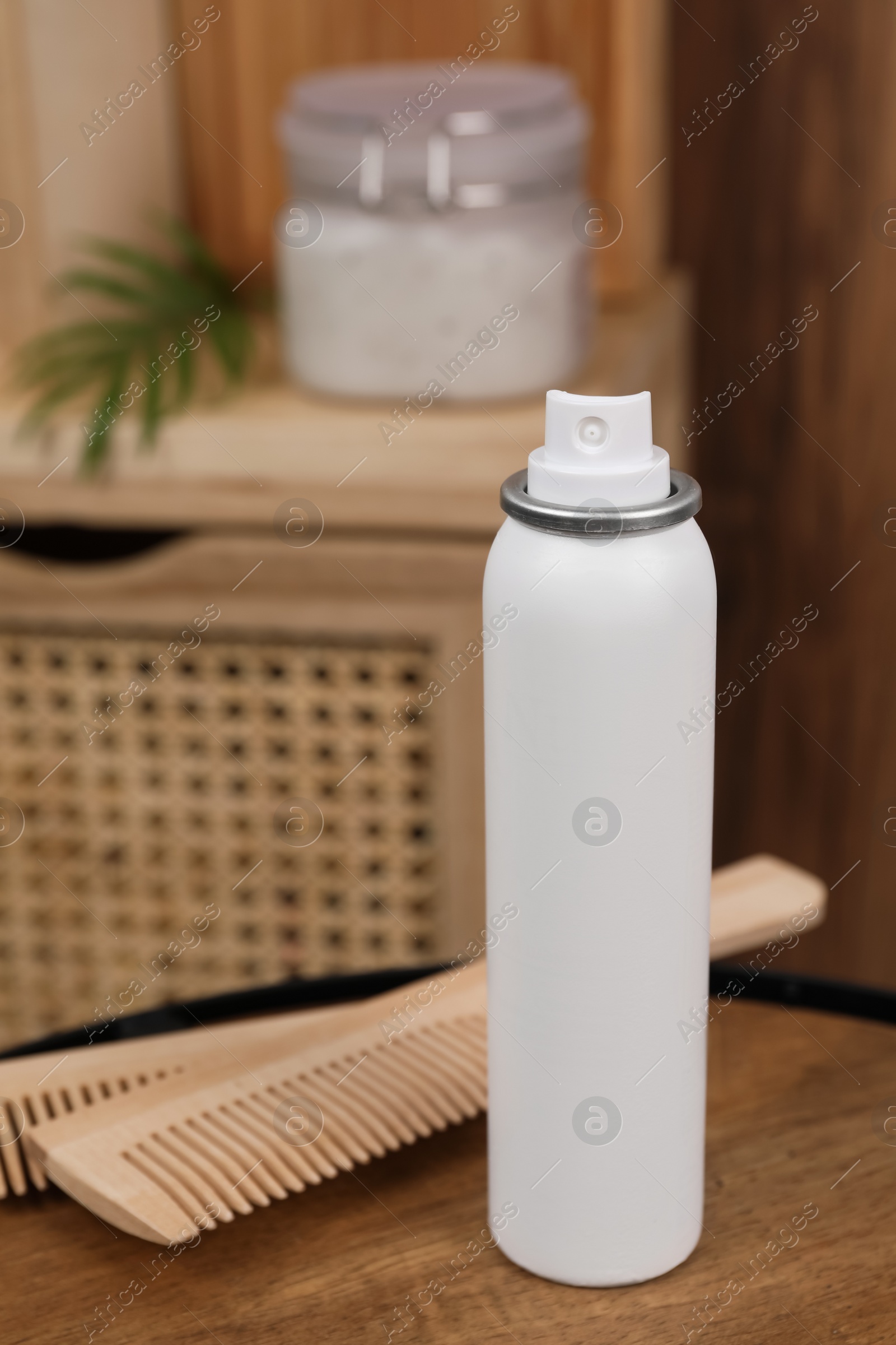 Photo of Dry shampoo spray and combs on wooden table in bathroom