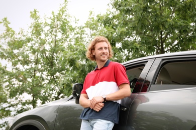 Photo of Attractive young man near luxury car outdoors
