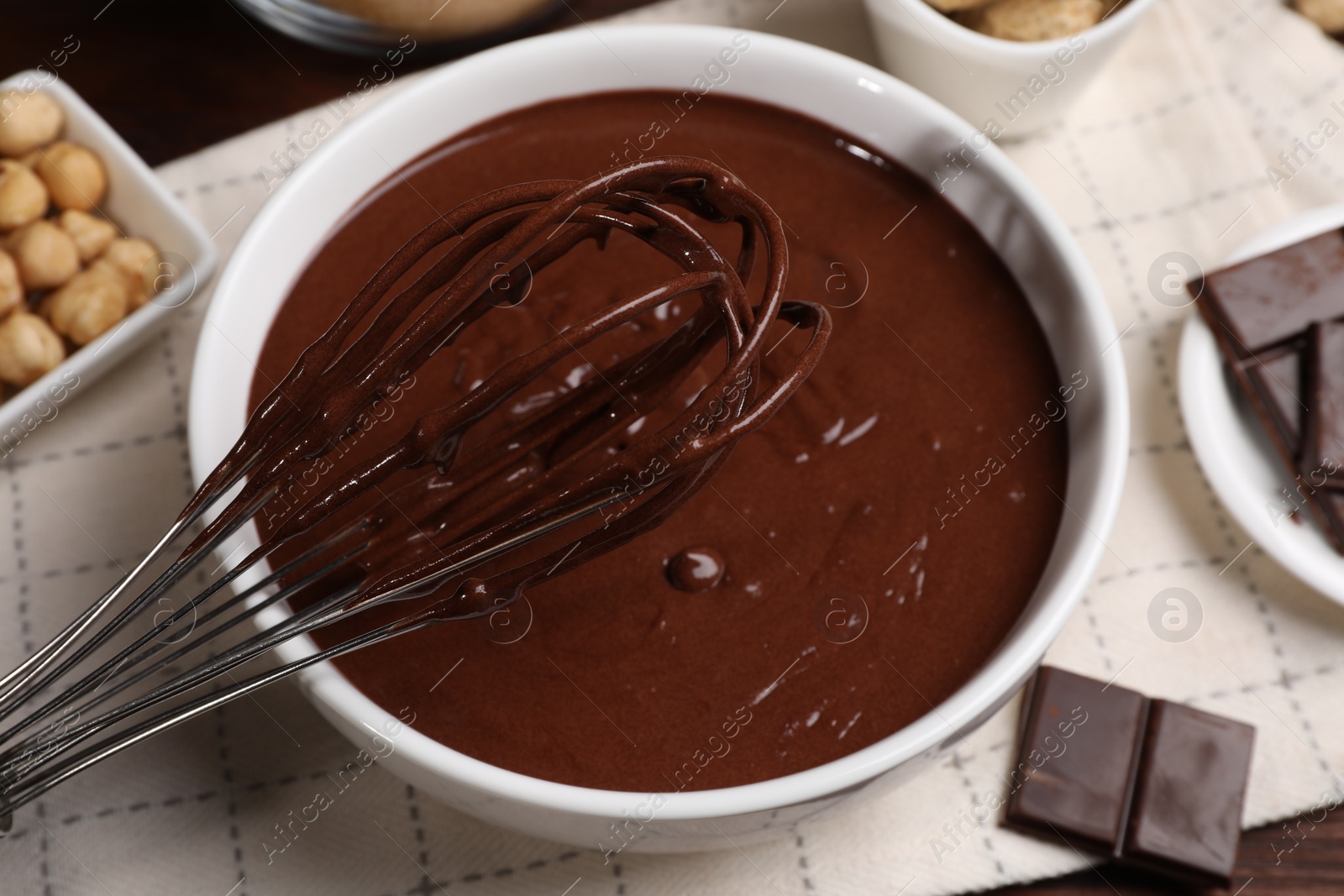 Photo of Bowl with chocolate cream and whisk on table, closeup