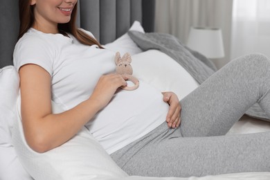 Pregnant woman with bunny toy in bedroom, closeup